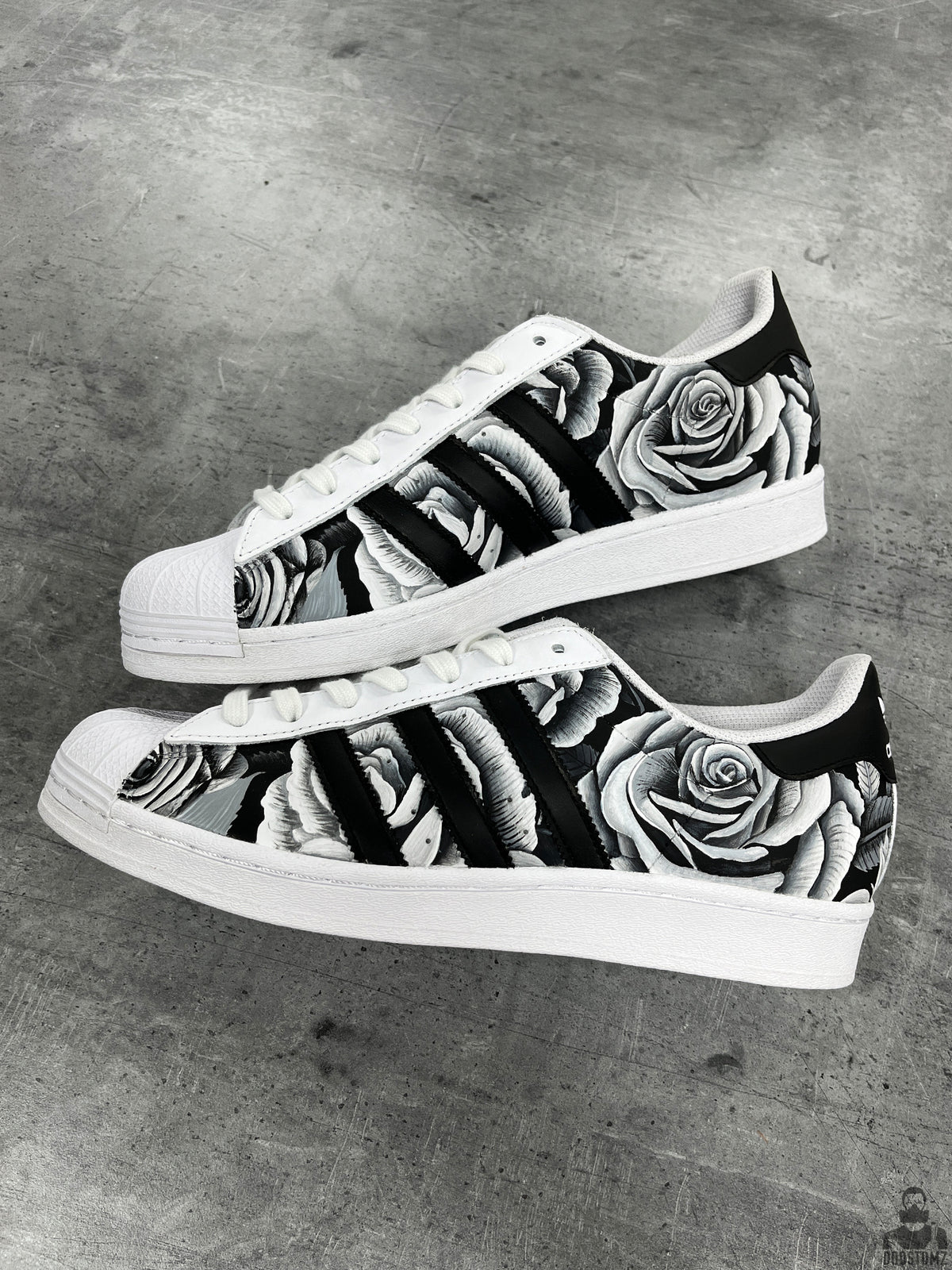 Pair of Adidas Superstar Black & White Roses Custom sneakers with monochrome floral artwork and white shell toes