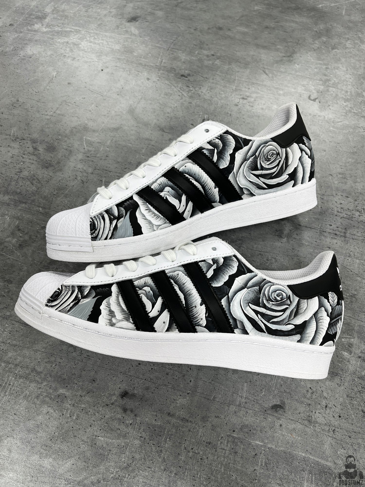Pair of Adidas Superstar Black & White Roses Custom sneakers with monochrome floral artwork and white shell toes