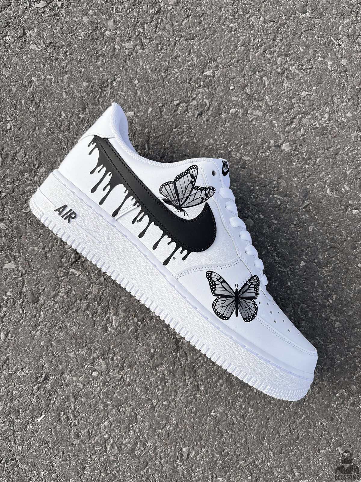 Side view of a custom Nike Air Force 1 with black paint drips and butterfly artwork