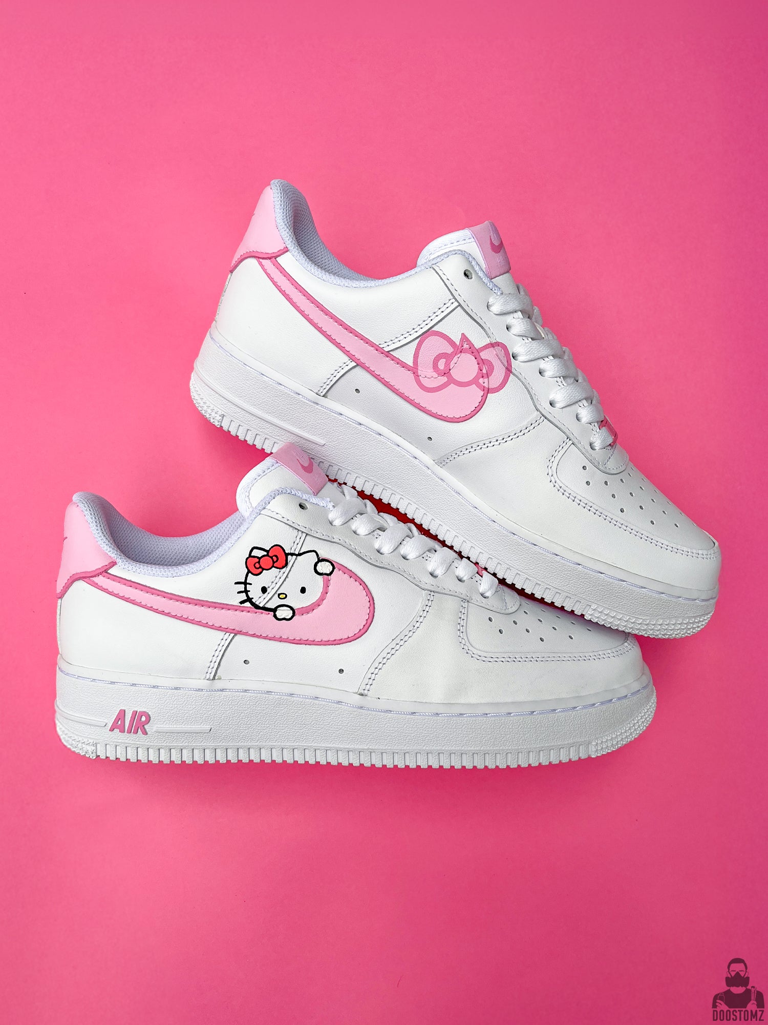 Pair of custom Nike Air Force 1 Hello Kitty sneakers featuring pink hand-painted details and playful artwork
