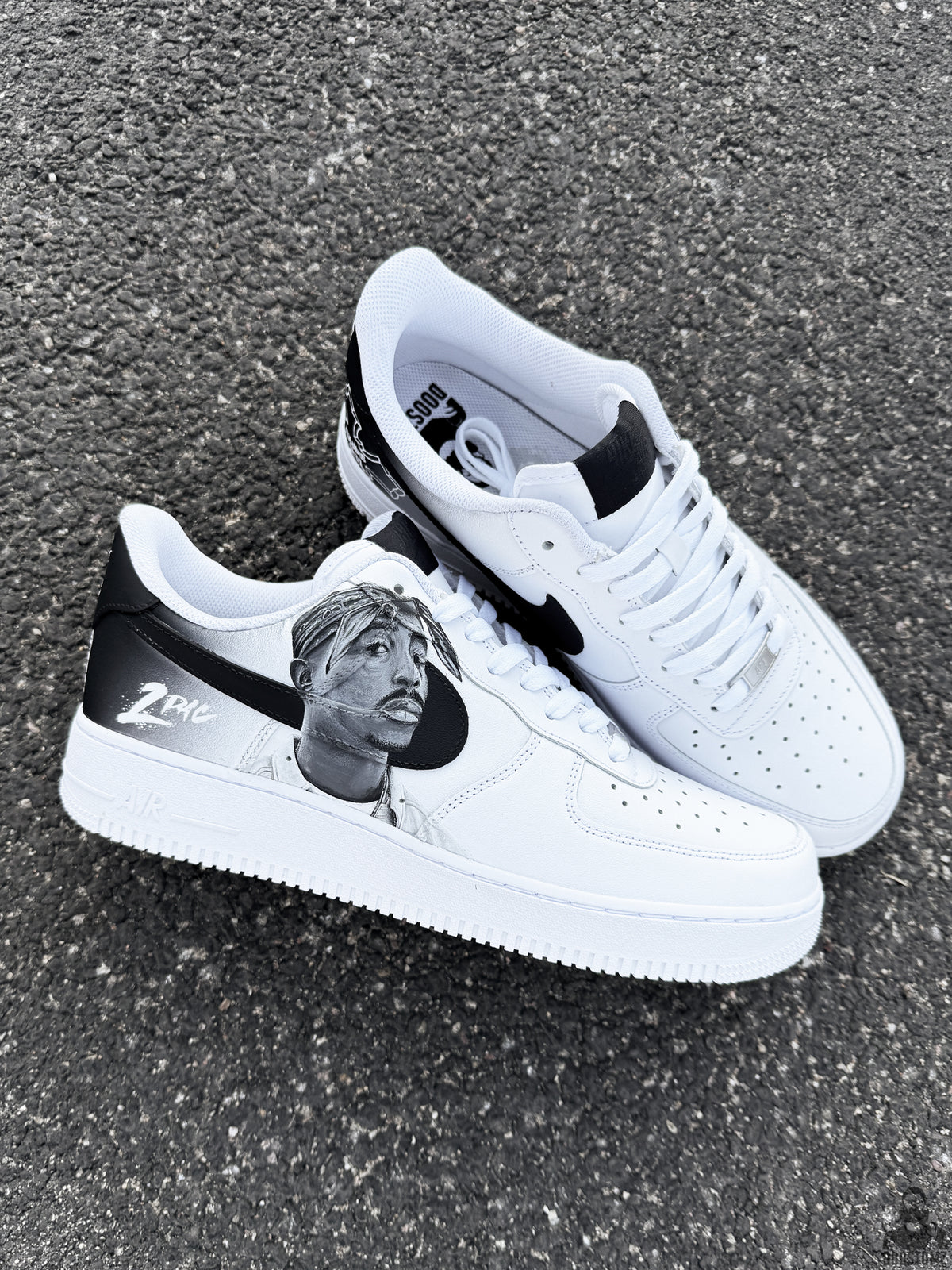 Pair of custom Nike Air Force 1 shoes featuring black and white hand painted Tupac Shakur inspired artwork on both sneakers